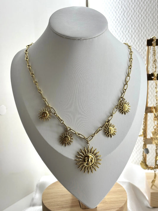 Collier doré avec pendentifs soleils sur mannequin.
