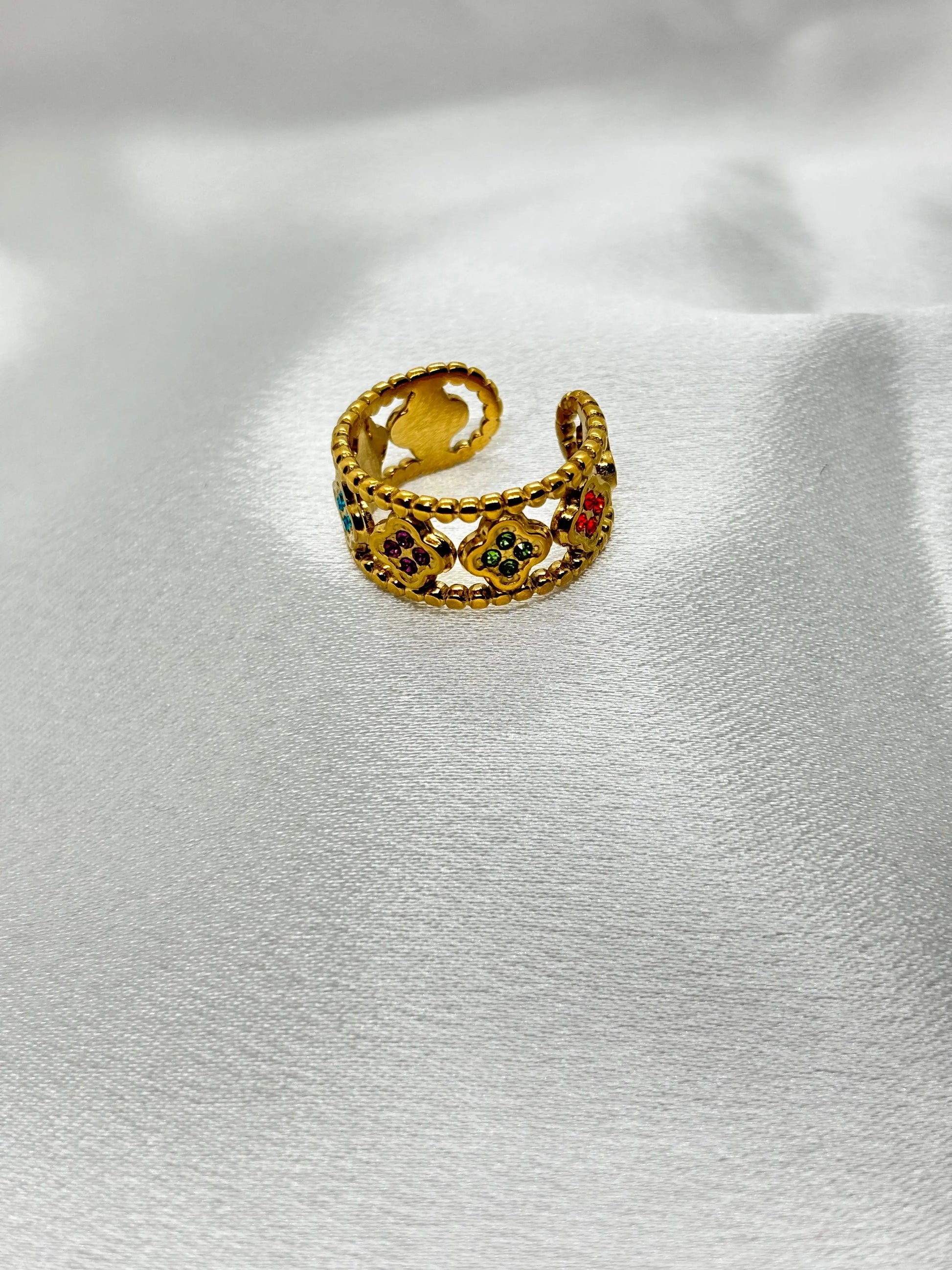 Bague dorée tendance TikTok avec motifs colorés et design ajouré délicat sur fond blanc