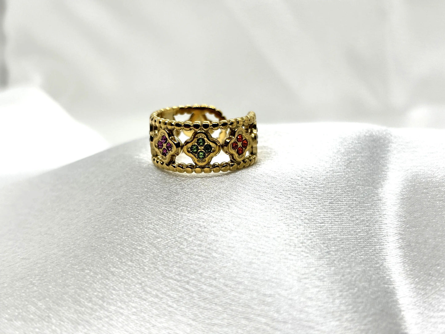 Bague dorée tendance TikTok avec pierres colorées élégantes sur fond blanc satiné