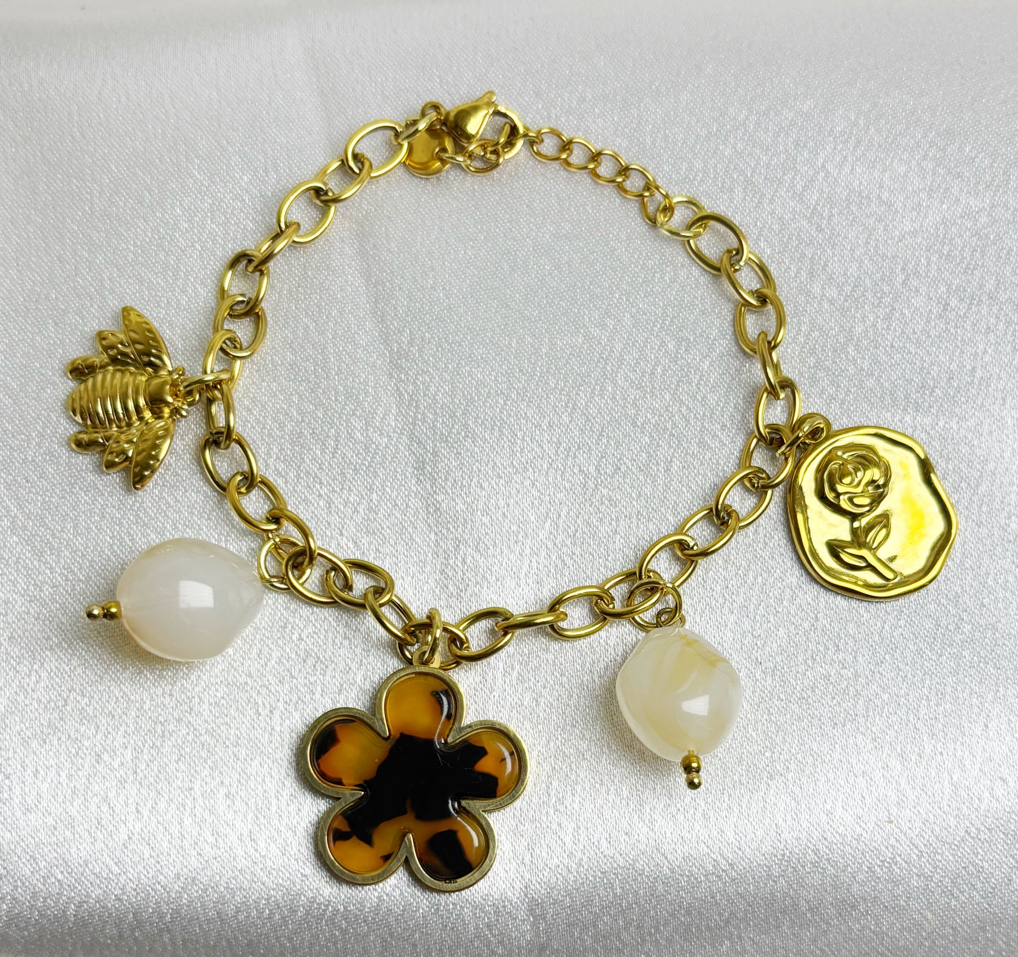 Bracelet doré avec charms incluant fleur, perles et pendentifs dorés de la marque EVAYA