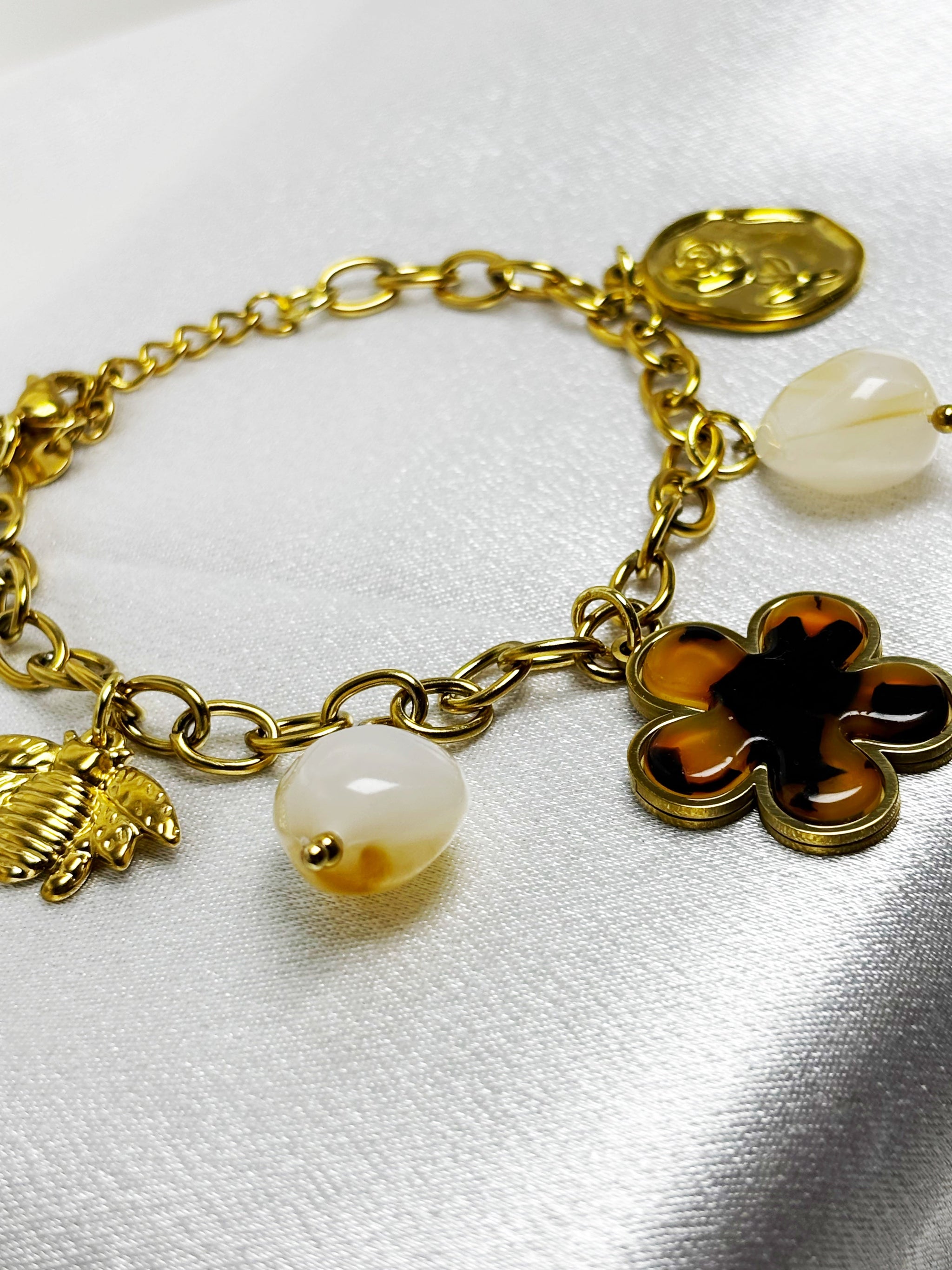 Bracelet doré avec charms par EVAYA incluant pendentifs en forme de fleur et perles décoratives