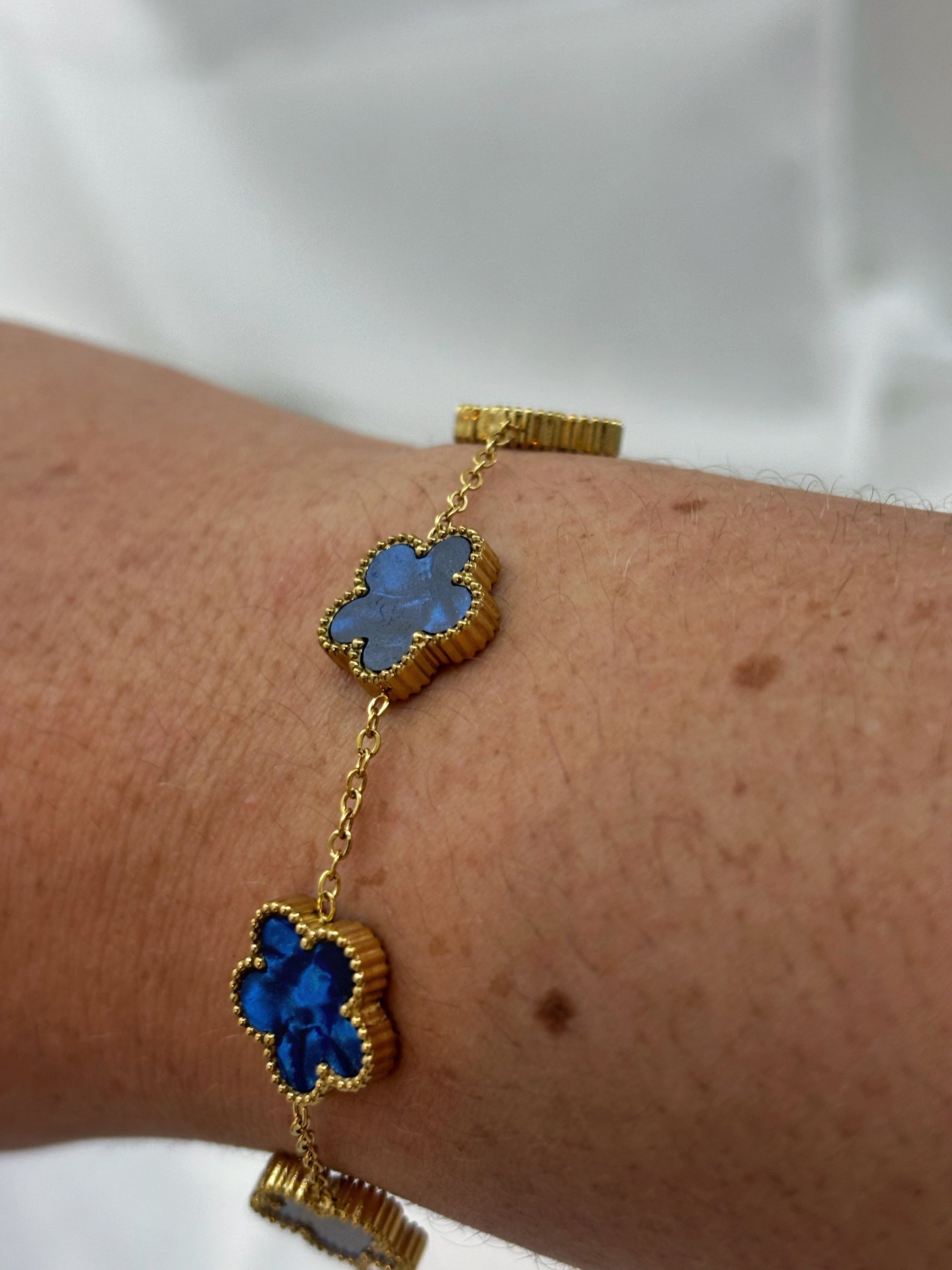 Bracelet fleur acier inoxydable avec fleurs bleues et chaîne dorée porté au poignet EVAYA