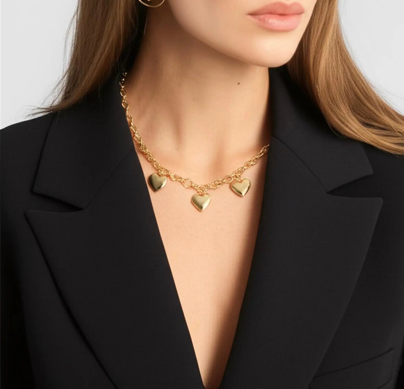 Collier doré pendentif breloque cœur acier inoxydable femme porté avec veste noire élégante