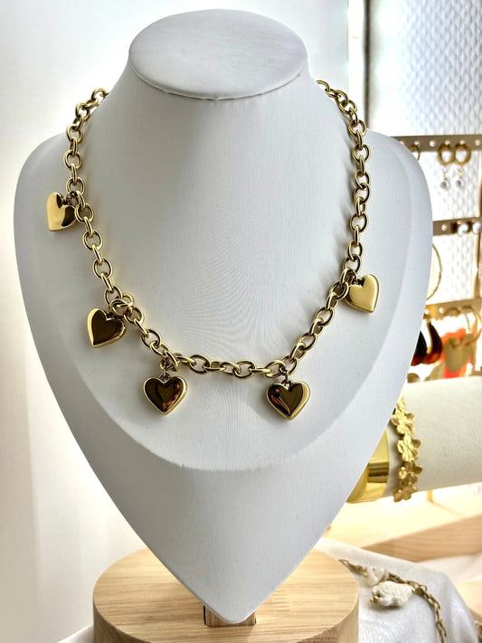 Collier doré pendentif breloque cœur acier inoxydable femme présenté sur un présentoir blanc