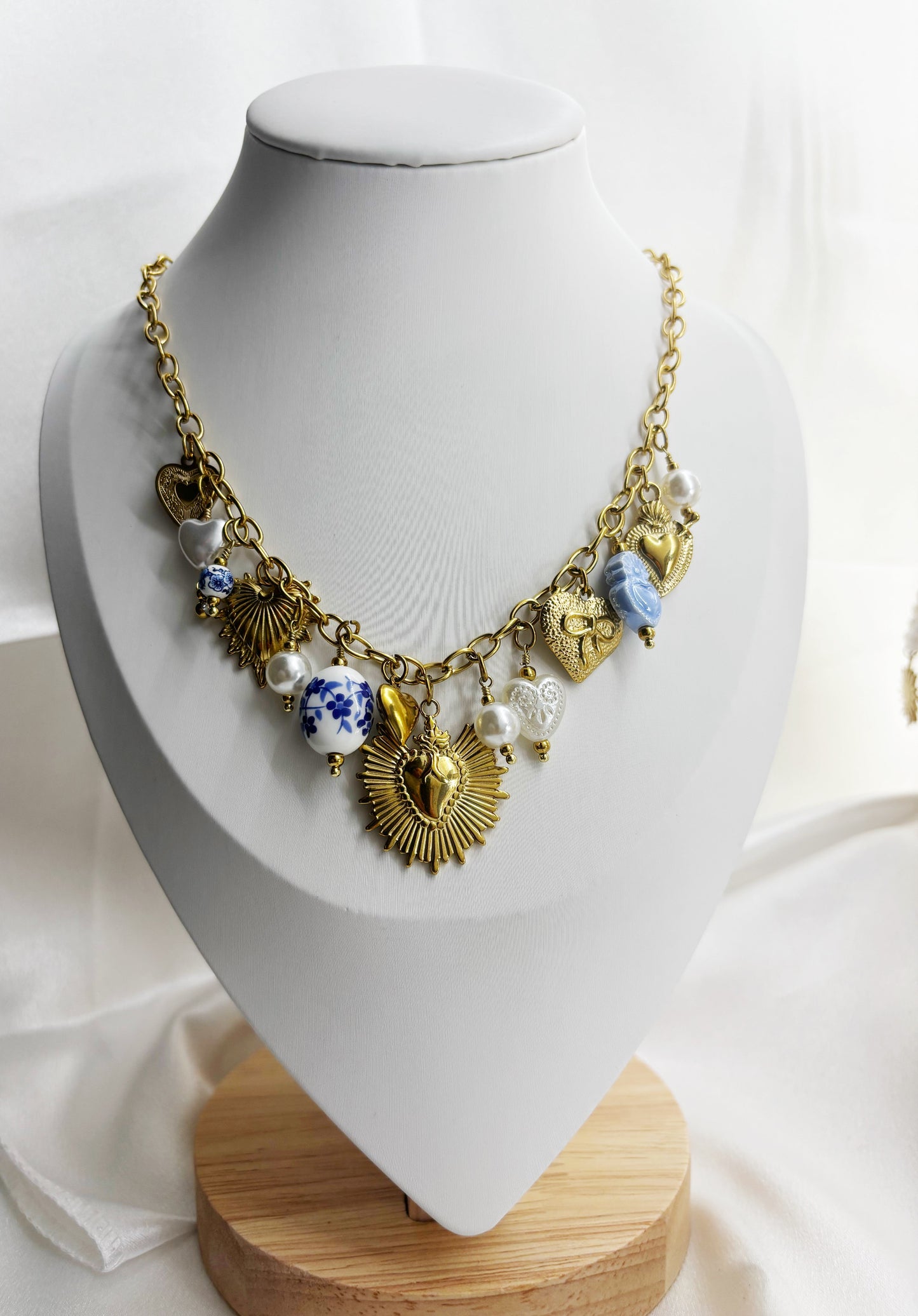 Collier original pendentifs dorés et perles sur chaîne dorée présenté sur un présentoir blanc