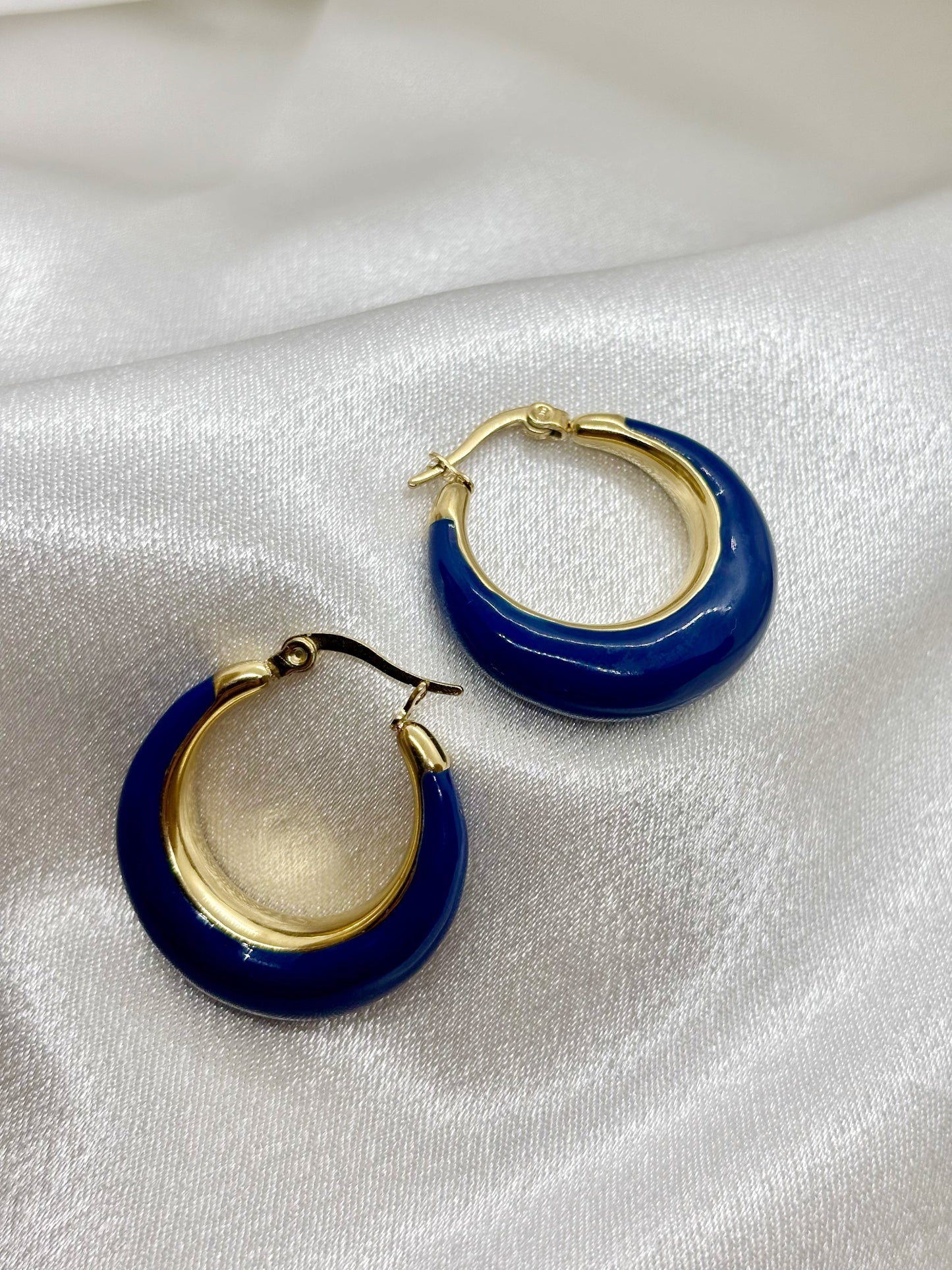 Boucles d'oreilles créoles or bleu acier inoxydable femme EVAYA sur fond de tissu blanc