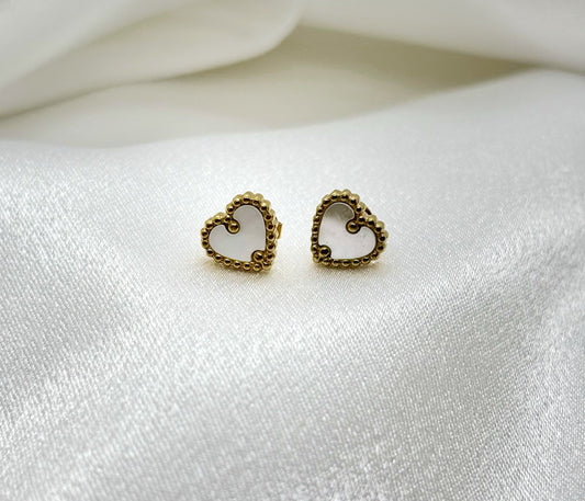 Petites boucles d’oreilles dorées chic coeur nacré en forme de cœur fines et élégantes sur tissu satiné blanc